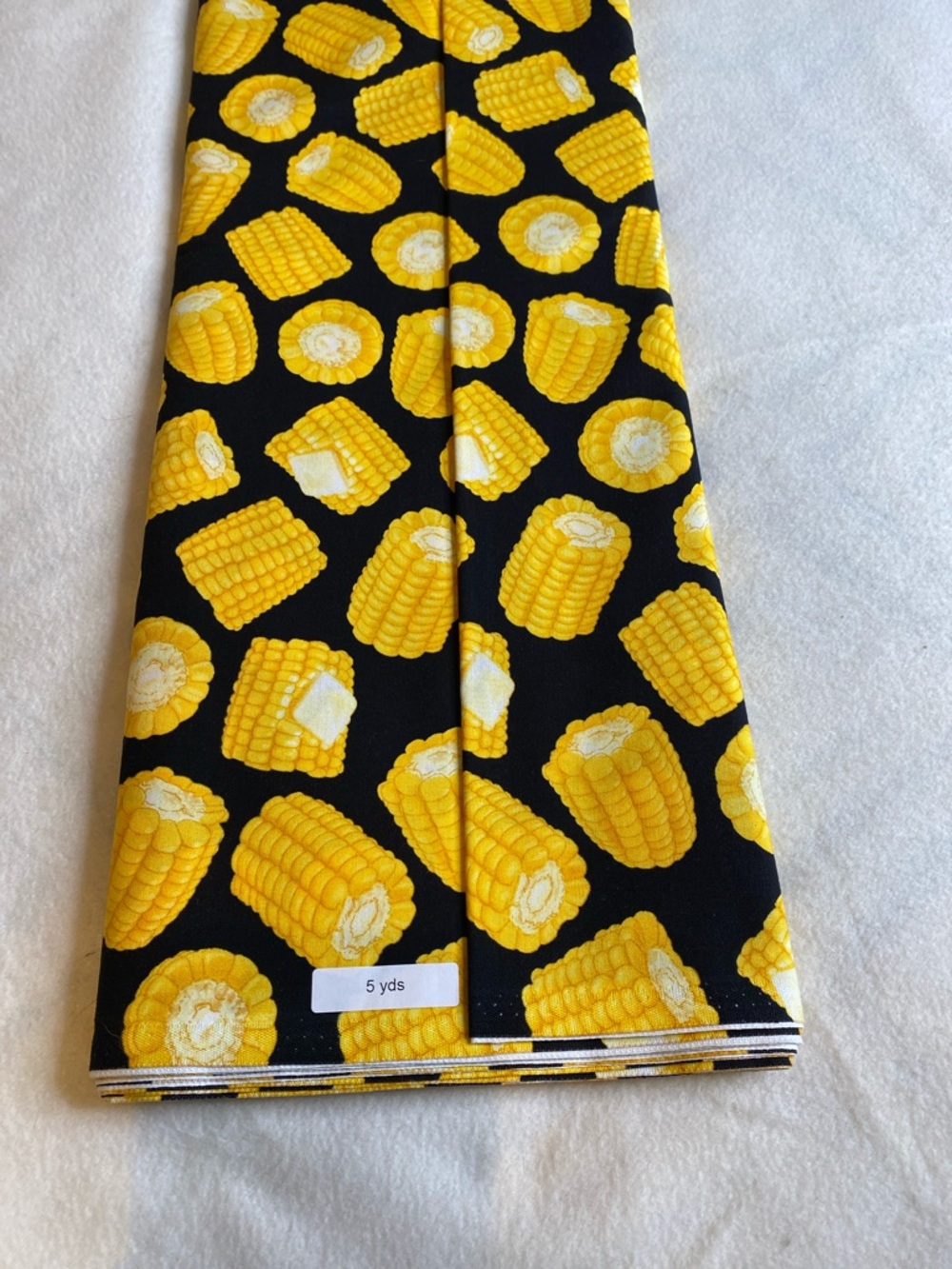 Five continuous yards of a buttered corn on a black background fabric novelty
